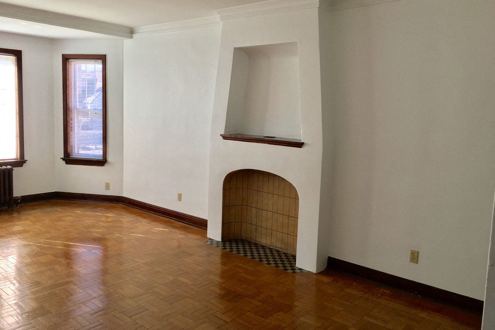 an empty living room with a fireplace and wooden floors