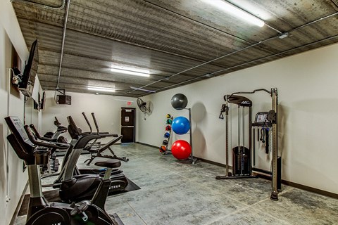 A gym with a row of treadmills and exercise balls.