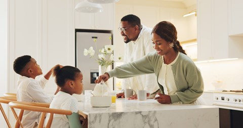 A family of four is gathered around a kitchen island.
