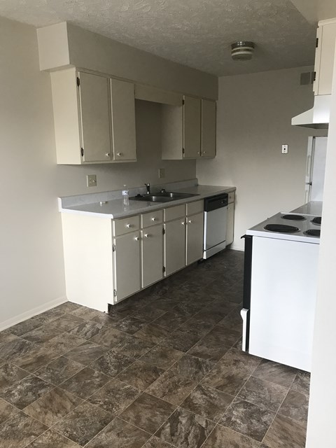 A kitchen with white cabinets and a tiled floor.