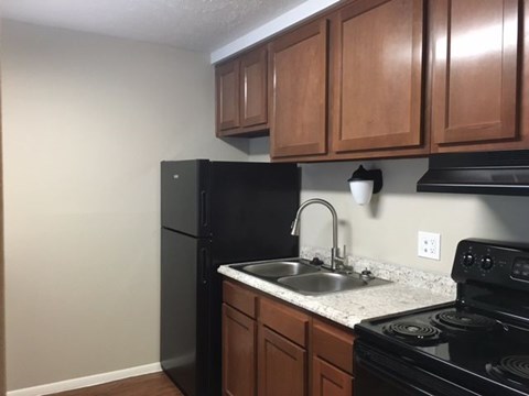 A kitchen with brown cabinets and black appliances.