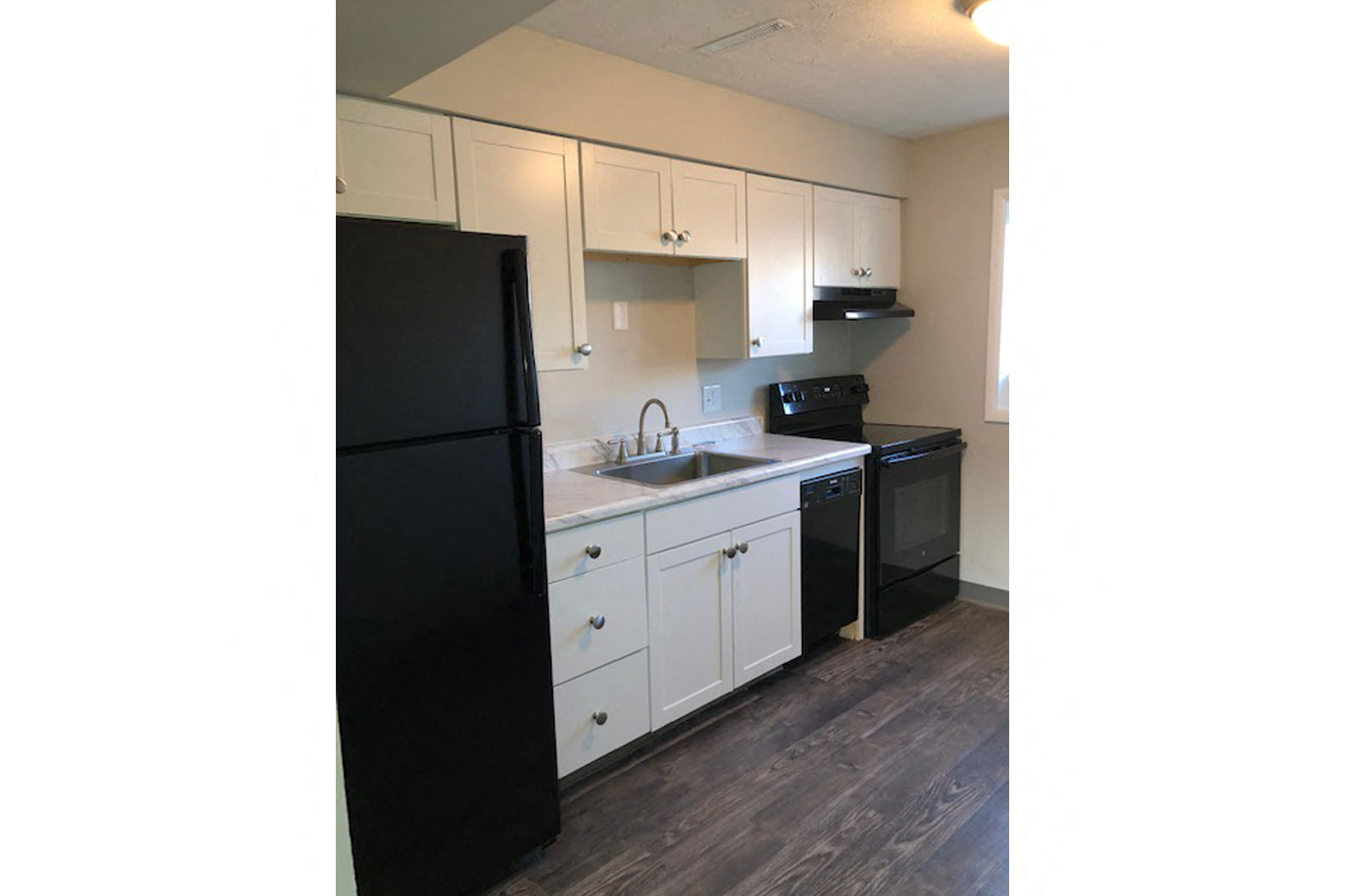 a kitchen with white cabinets and a black refrigerator