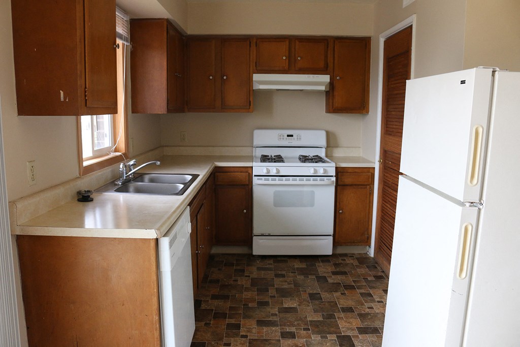 an empty kitchen with white appliances and wooden cabinets