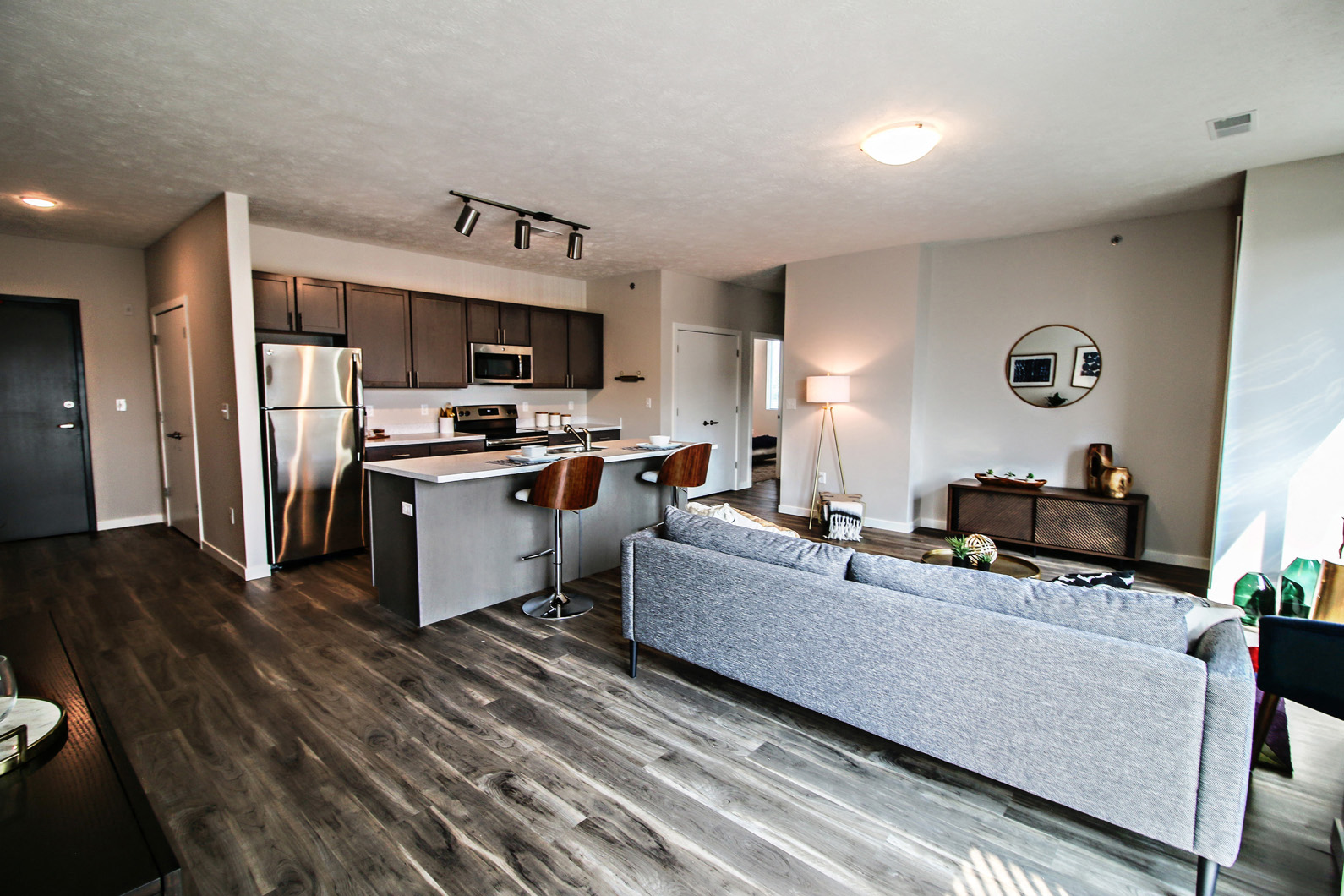 spacious living room and kitchen with stainless steel appliances and a couch