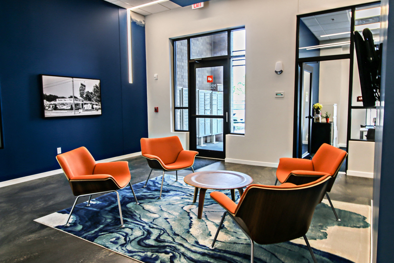 a lounge area with orange chairs and a table