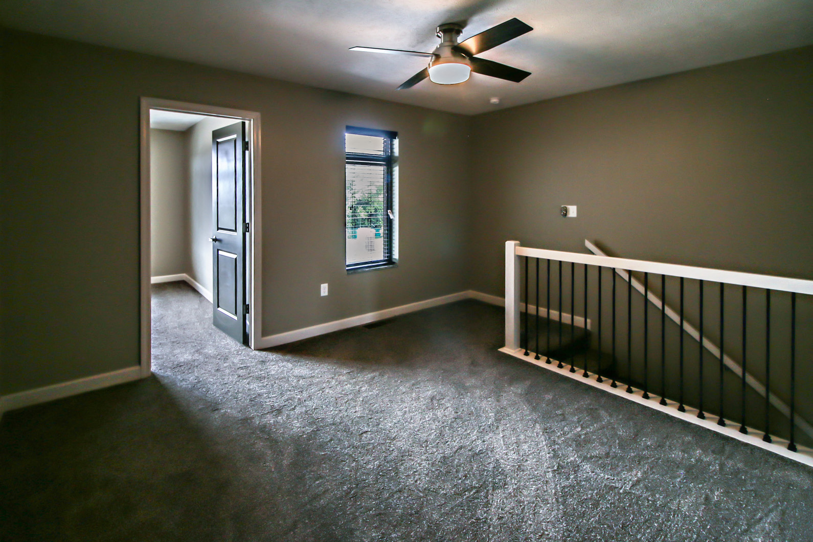 an empty living room with a staircase and a ceiling fan