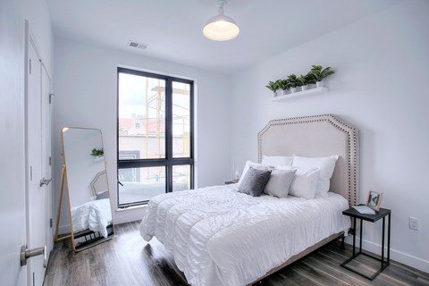 A bedroom with a large bed and a window overlooking a cityscape.