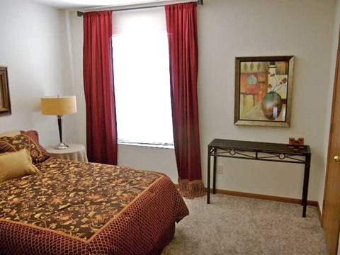 a bedroom with a bed and a window with red curtains
