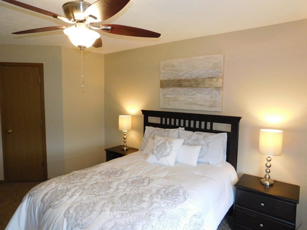 a bedroom with a large bed and a ceiling fan