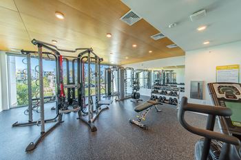 A gym with a variety of equipment including treadmills, weights, and exercise machines.