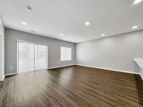 A spacious room with wooden flooring and white walls.