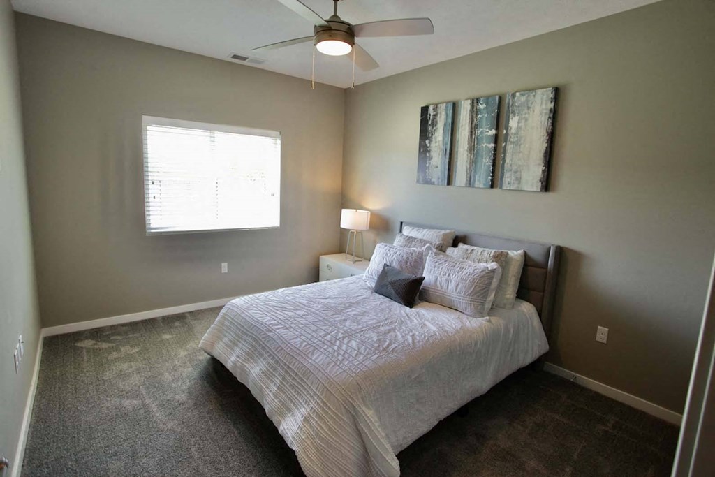 A bedroom with a bed, a ceiling fan, and a window.