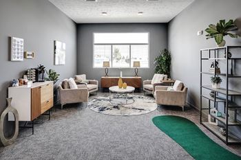 A living room with a grey carpet and a green rug.