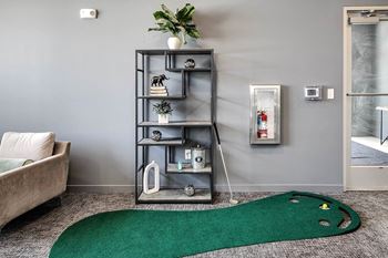 A grey shelf with various decorative items stands in a room with a green rug on the floor.