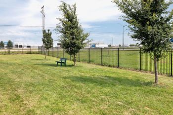 A park with a green bench and a black fence.