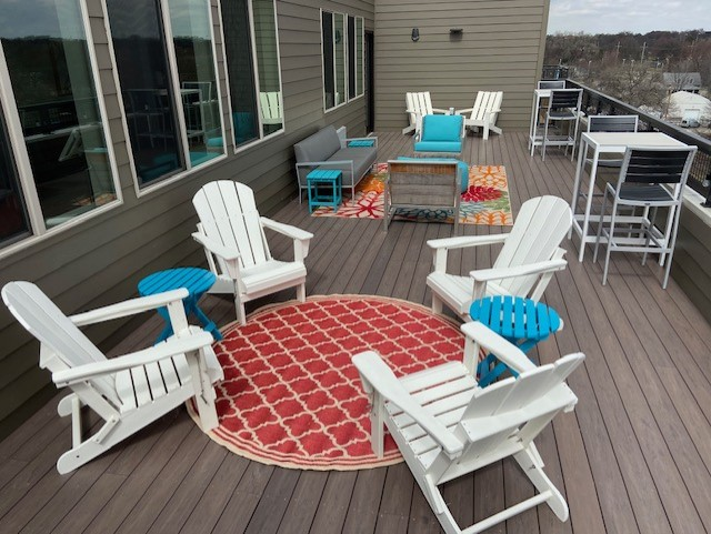 a patio with rocking chairs and a rug on a deck