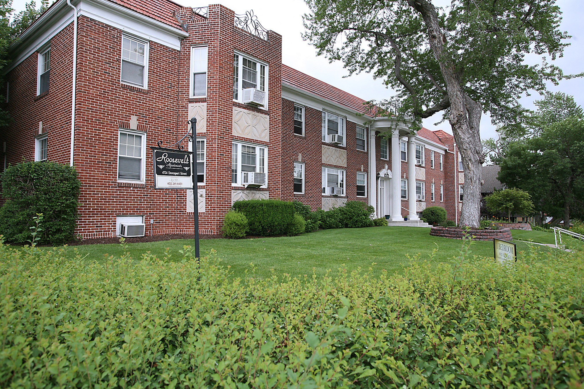 a large brick building with a green lawn in front of it