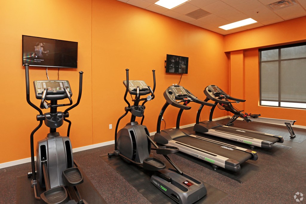 a gym with exercise equipment and a television