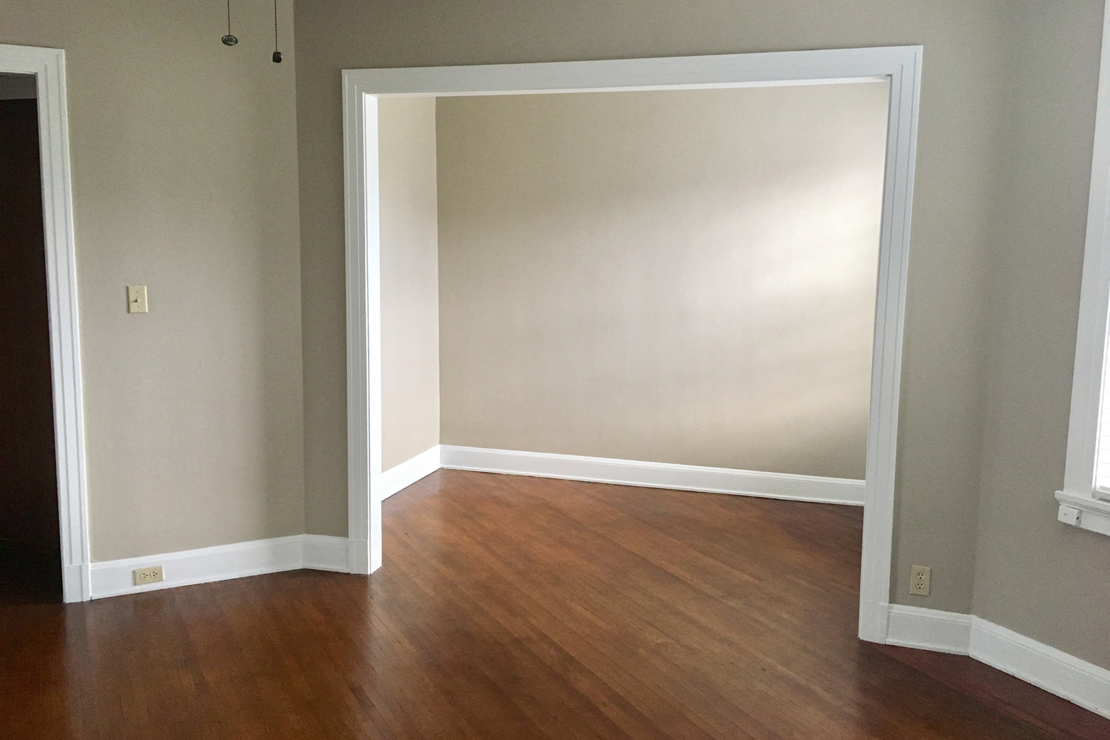 an empty room with a hard wood floor and an open doorway