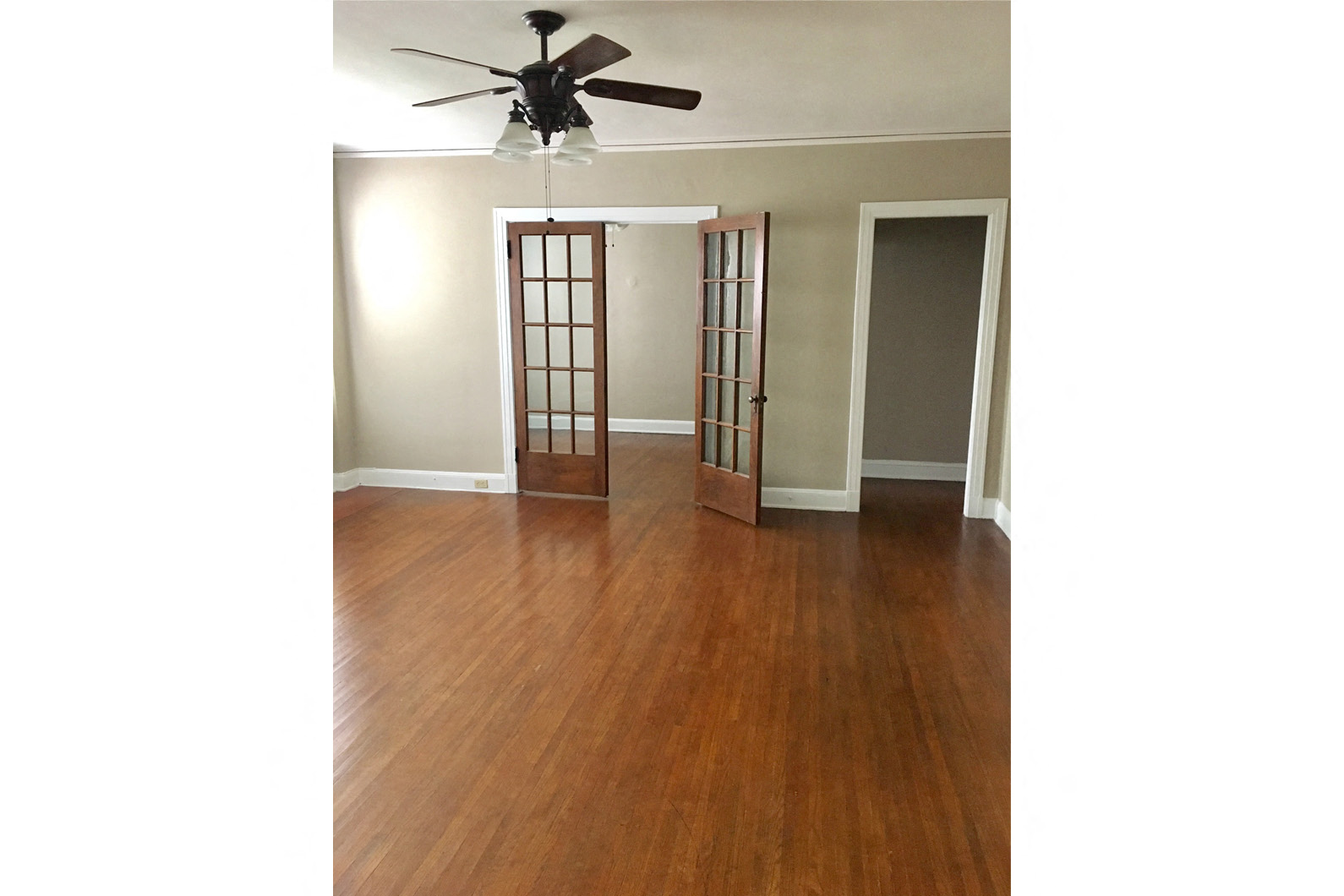 an empty living room with wood floors and a ceiling fan