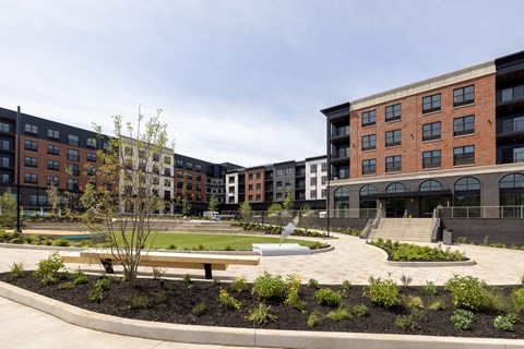 A courtyard with a bench and a tree in front of apartment buildings.