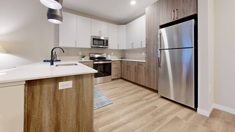A modern kitchen with a stainless steel refrigerator and wooden cabinets.