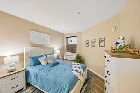 A bedroom with a bed, nightstand, and a dresser.