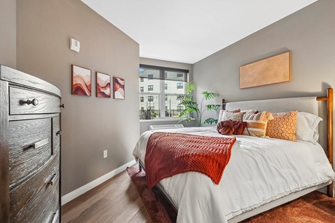 A bedroom with a large bed and a wooden dresser.