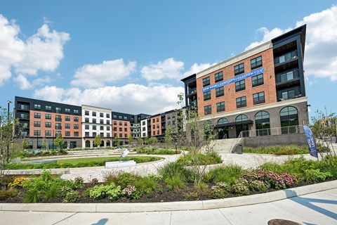 A modern building complex with a landscaped garden in front.