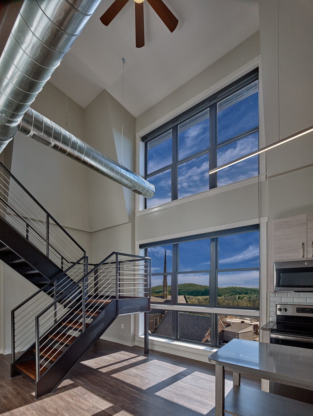 a large living room with a staircase and large windows at 520 Lofts, Allentown, Pennsylvania