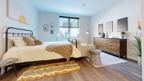A bedroom with a bed, a chair, and a dresser.