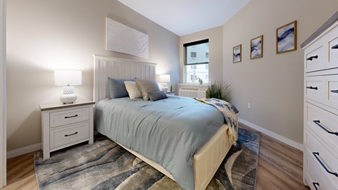 A bedroom with a bed, nightstand, and a rug.