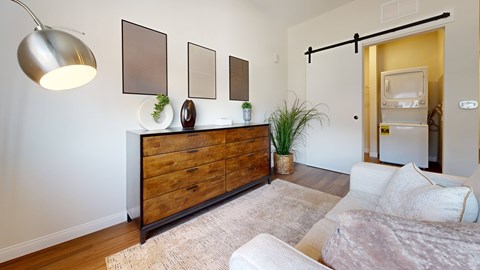 A modern living room with a wooden dresser and a white couch.