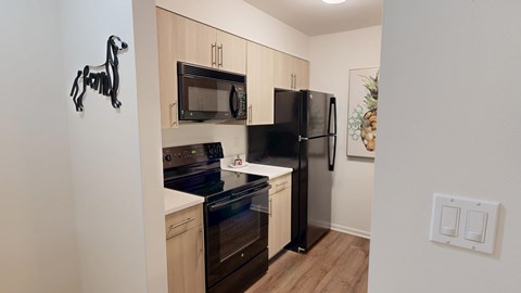 A kitchen with a black fridge and stove top oven.