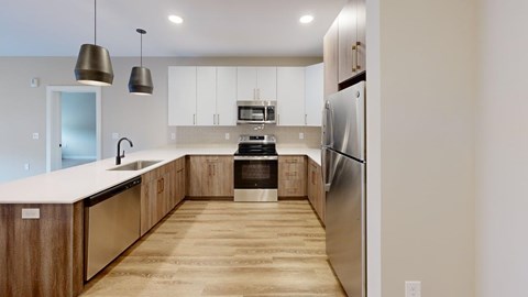 A modern kitchen with wooden floors and stainless steel appliances.