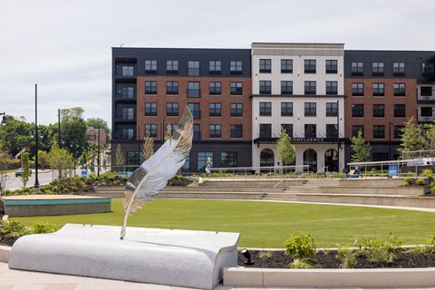 A large white feather is sticking out of a grey pedestal in front of a building.