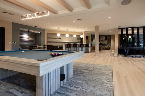 A pool table is in the middle of a room with a wooden floor.