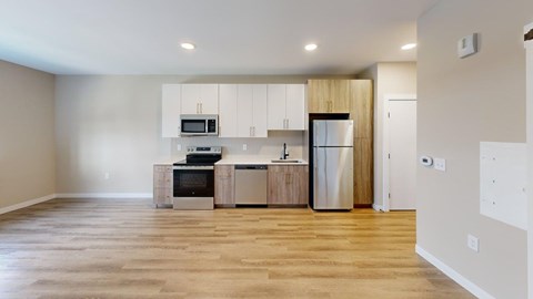 A kitchen with a refrigerator, microwave, oven, and sink.
