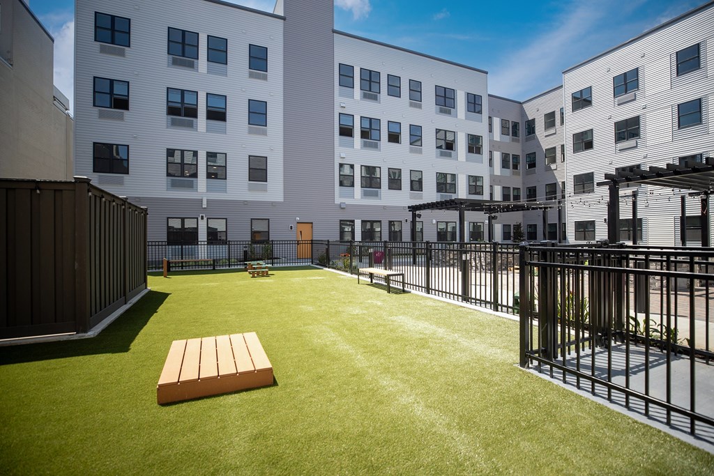 A grassy courtyard with a bench and a fence.