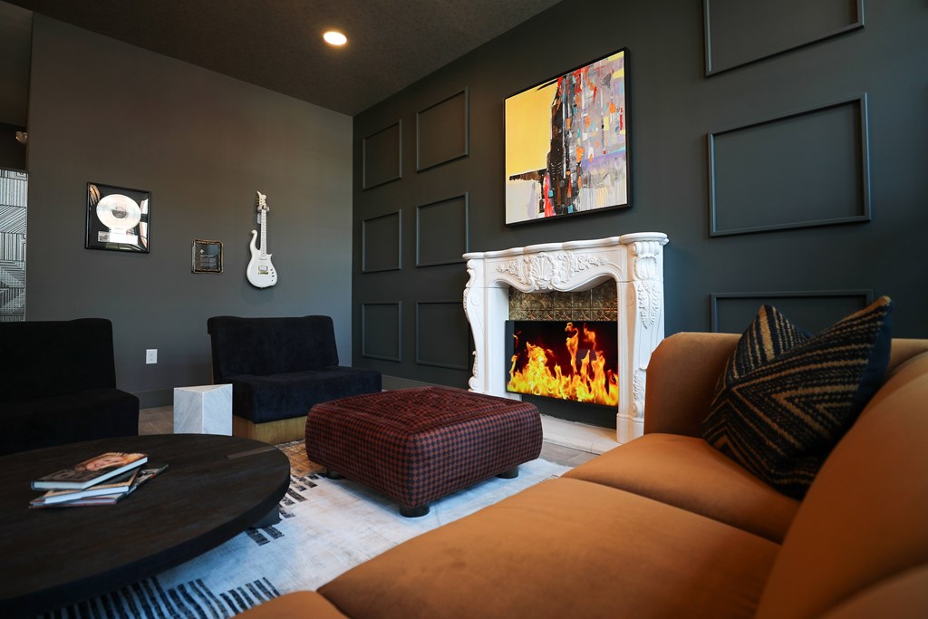 A living room with a fireplace and a guitar picture frame on the wall.