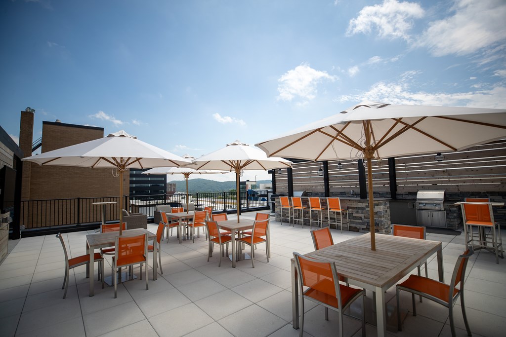 A patio with tables and chairs and umbrellas.