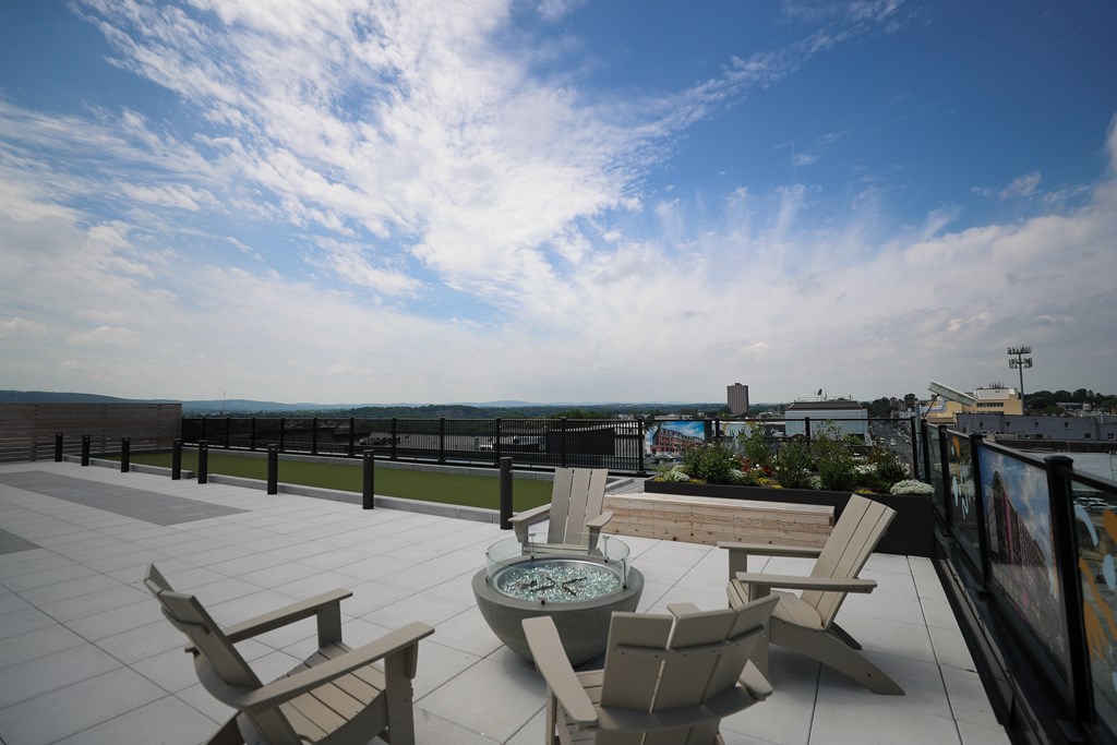 A patio with a hot tub and chairs overlooking a cityscape.