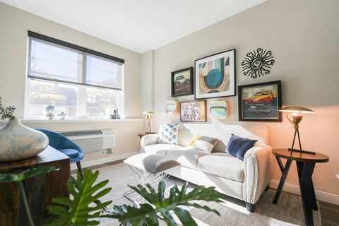 A living room with a white couch, a blue chair, and a table with a vase on it.