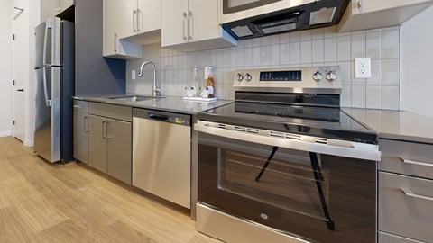A modern kitchen with stainless steel appliances and wooden flooring.