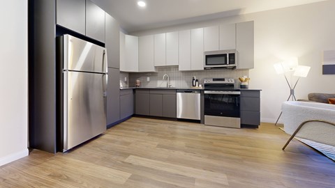 A modern kitchen with a refrigerator, microwave, oven, and sink.