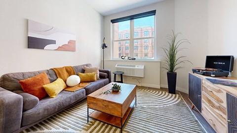 A living room with a grey couch, a wooden coffee table, and a flat screen TV.