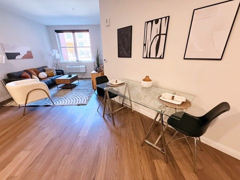 A living room with a glass table and a black chair.