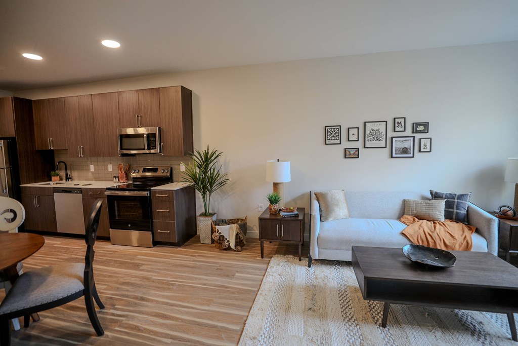 A modern living room with a couch, coffee table, and kitchen area.