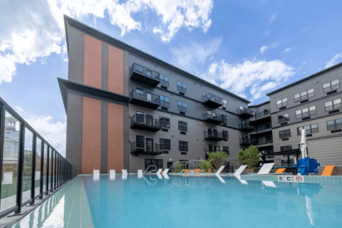 A swimming pool in front of a modern building with a clear blue sky above.