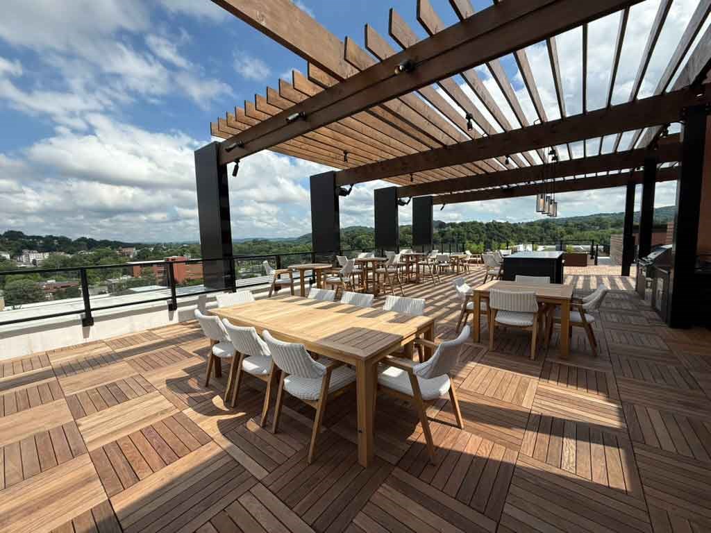 A wooden deck with tables and chairs and a pergola.